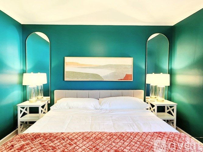 A bedroom with a large bed and two lamps.