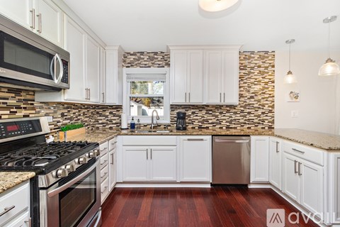 A kitchen with white cabinets and a stone backsplash.