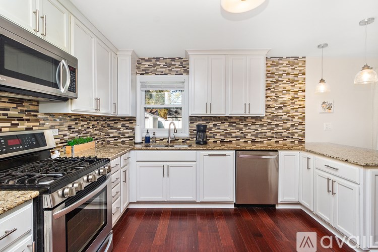 A kitchen with white cabinets and a stone backsplash.