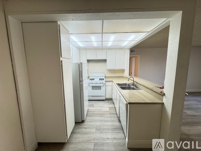 A kitchen with white appliances and cabinets is available for rent.