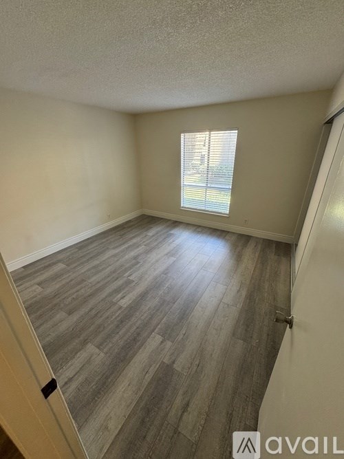 A room with wooden flooring and a window with blinds.