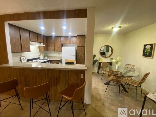 A kitchen with wooden cabinets and a counter with chairs around it.