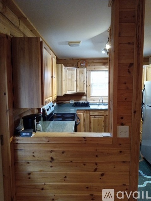 A wooden kitchen with a refrigerator on the right.