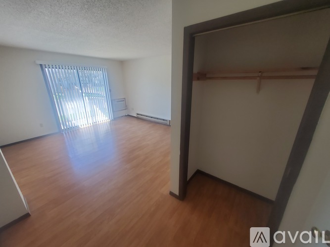 A room with wooden flooring and a large window with blinds.