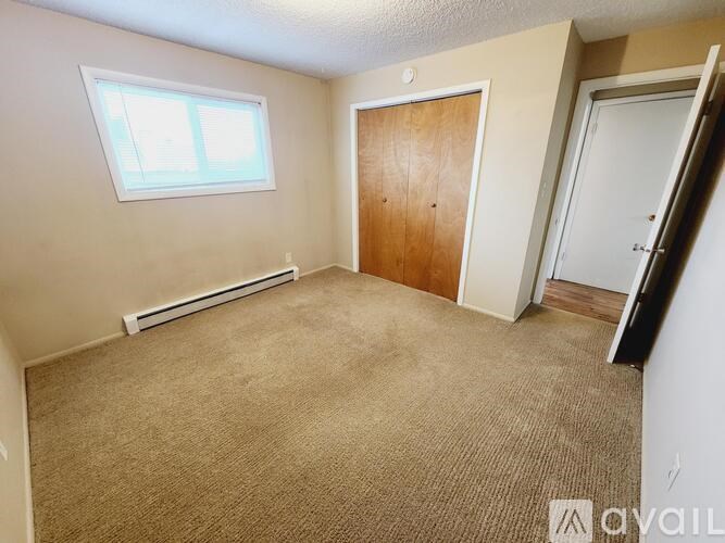A room with a window, carpet, and two doors.