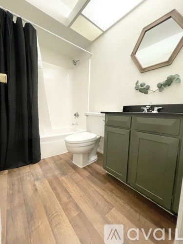 A bathroom with a toilet, sink, and mirror.