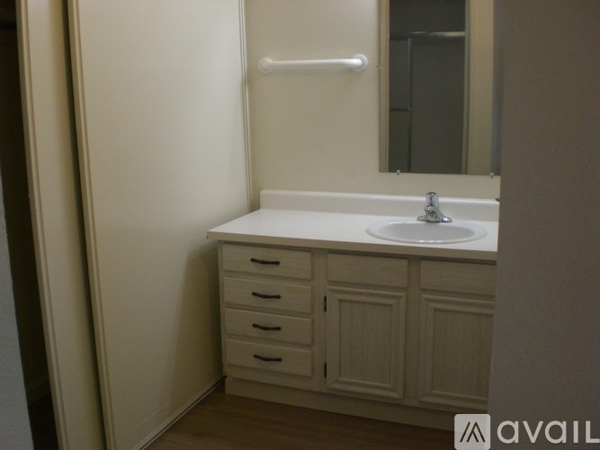 A bathroom with a sink, mirror, and cabinets.