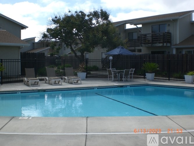 A pool with a blue umbrella and chairs around it.