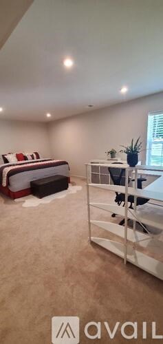 A bedroom with a bed, a desk, and a chair.