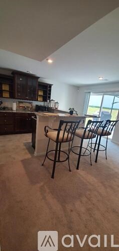 A kitchen with dark wood cabinets and a bar area with four stools.