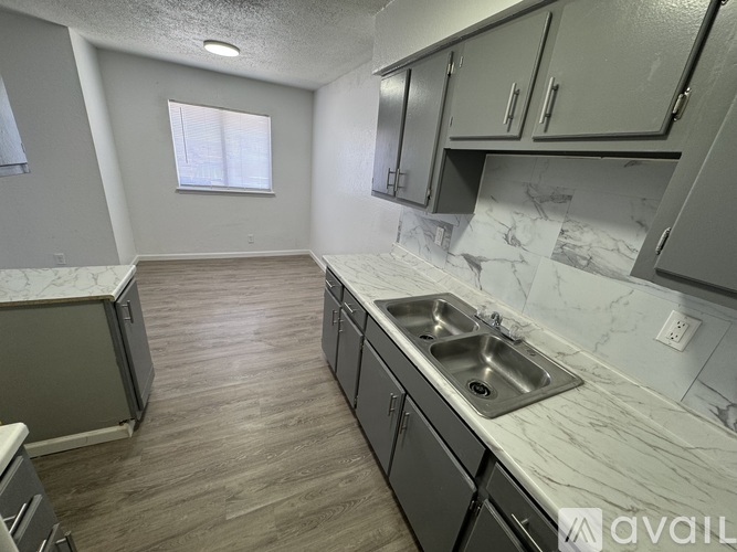 A kitchen with a marble countertop and wooden flooring.