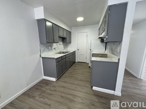 A kitchen with grey cabinets and a white countertop is available for rent.