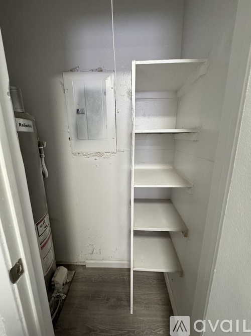 A white shelving unit in a room with a door on the left.
