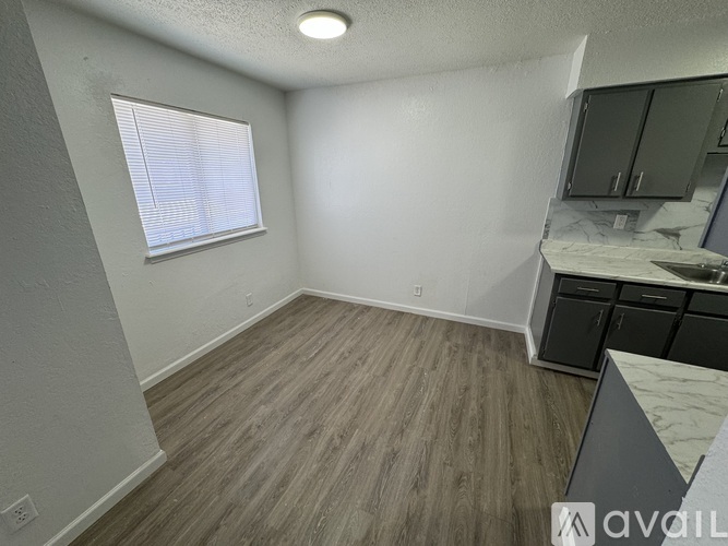 A room with wooden flooring and a window with blinds.