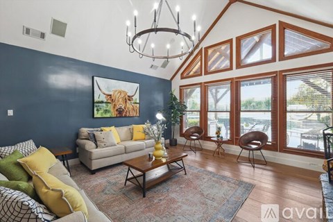A living room with a couch, chairs, and a painting of a cow.