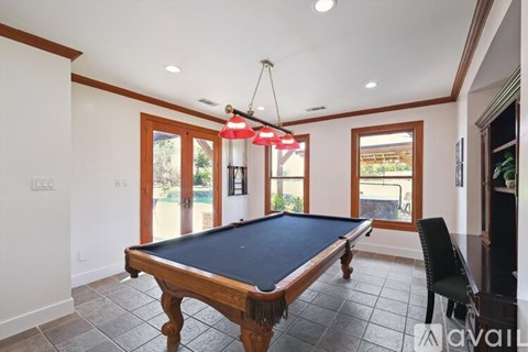 A pool table in a room with a light hanging from the ceiling.