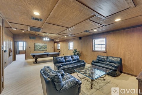A living room with a pool table and leather couches.