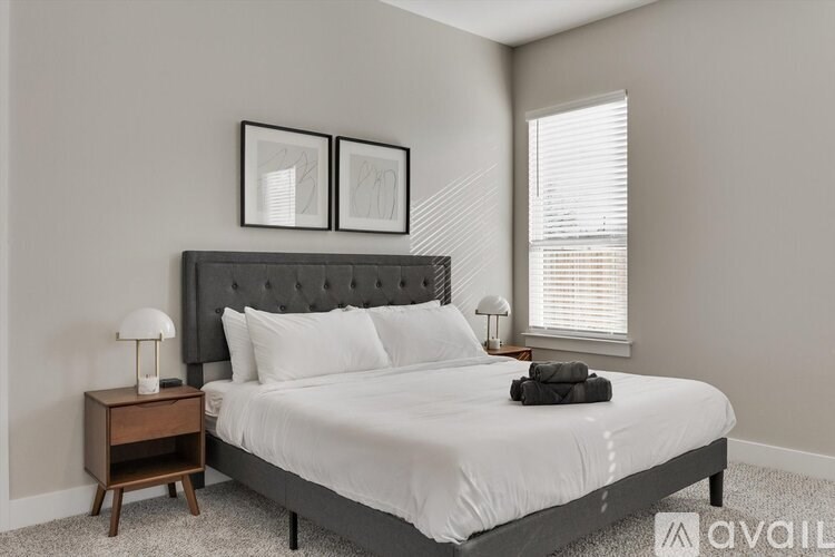 A bedroom with a large bed and two lamps on side tables.