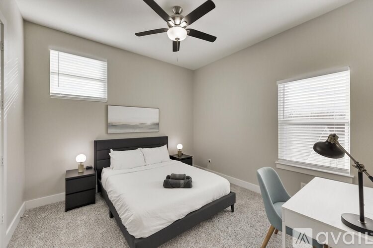 A bedroom with a bed, a chair, and a ceiling fan.