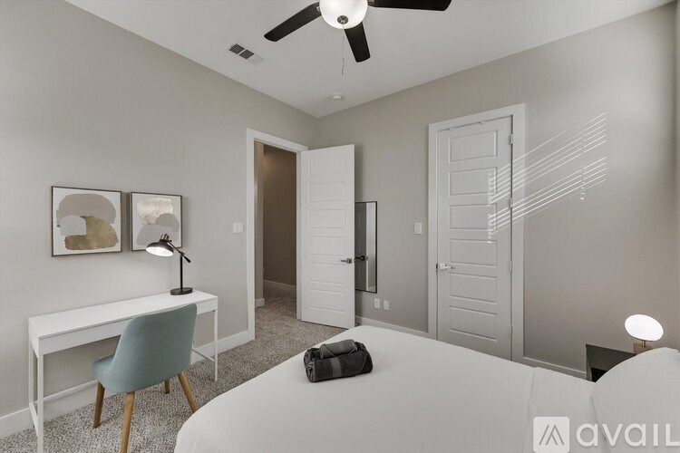 A bedroom with a bed, desk, chair, and a ceiling fan.