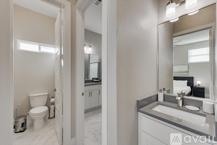 A bathroom with a toilet, sink, and mirror.