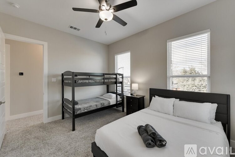 A bedroom with a bed, a bunk bed, and a ceiling fan.