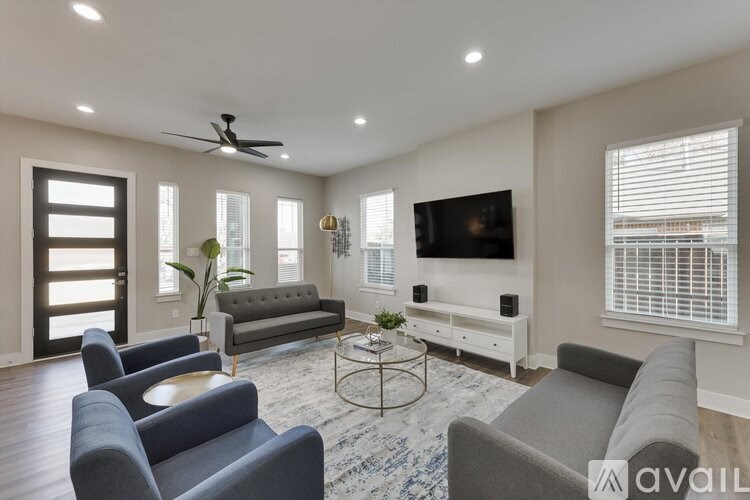 A living room with a grey couch, a coffee table, and a flat screen TV mounted on the wall.