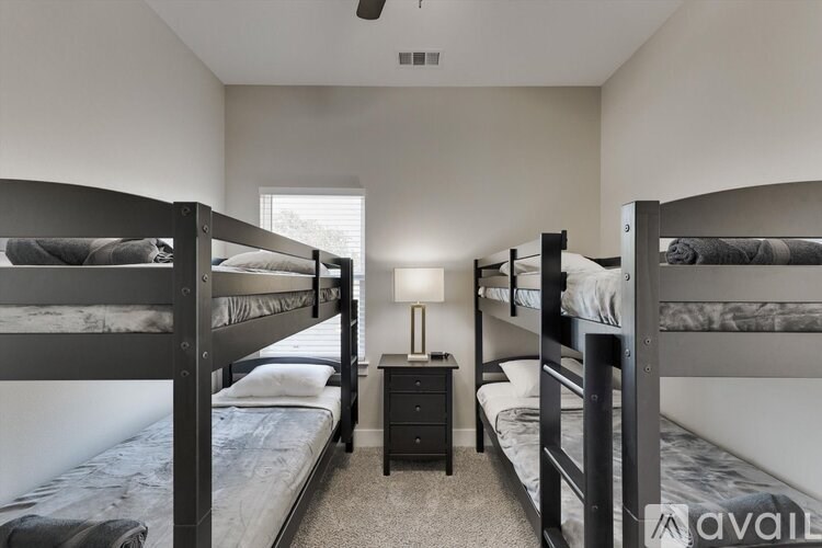 A room with bunk beds and a nightstand with a lamp.