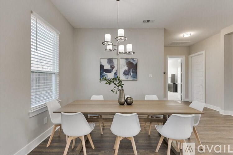 A dining room with a wooden table and white chairs.