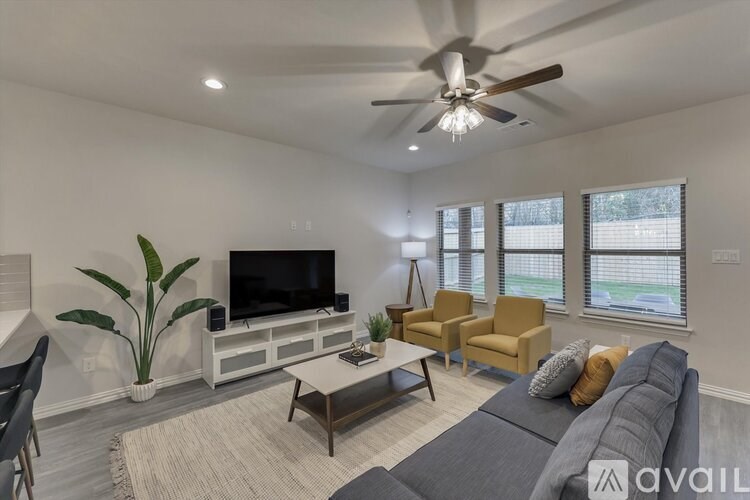 A living room with a grey couch, a television, and a ceiling fan.