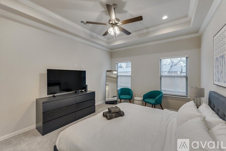 A bedroom with a large bed, a flat screen TV, and a ceiling fan.