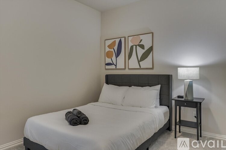 A bedroom with a bed, a nightstand with a lamp, and two framed pictures on the wall.