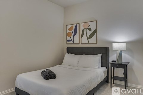 A bedroom with a bed, a nightstand with a lamp, and two framed pictures on the wall.