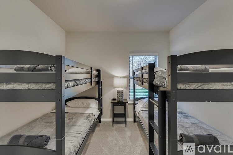 A room with two bunk beds and a small table in between.