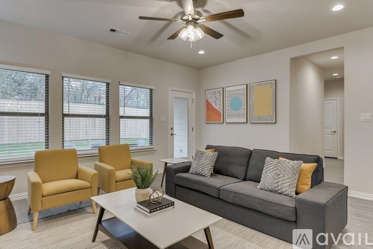A living room with a grey couch, a yellow chair, and a white coffee table.