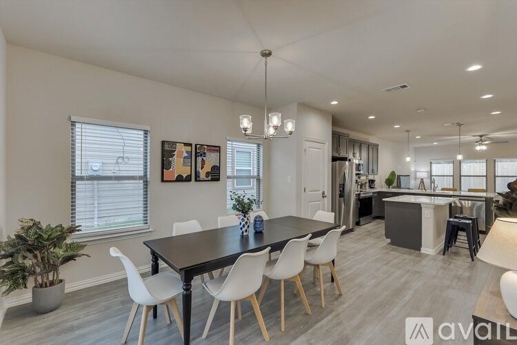 A modern dining room with a black table and white chairs.