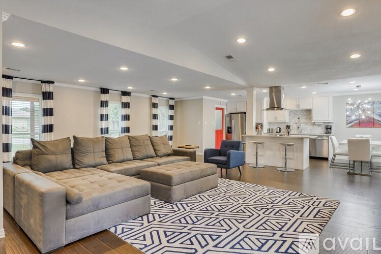 A modern living room with a grey sofa and a patterned rug.