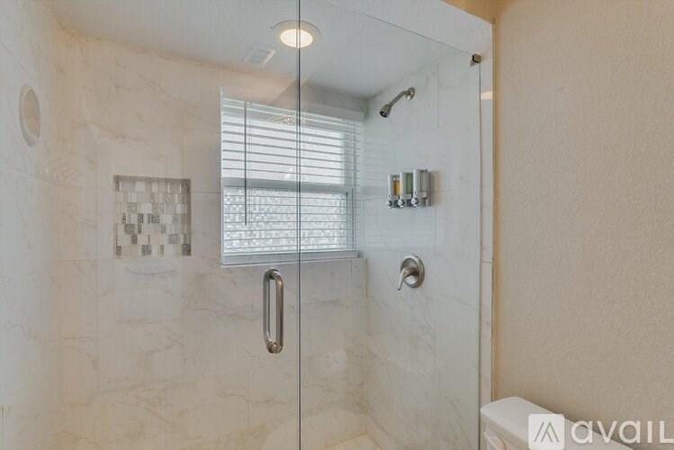 A bathroom with a glass shower door and a toilet.