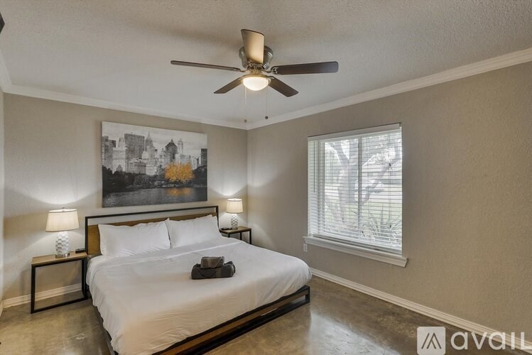 A bedroom with a bed, two lamps, and a ceiling fan.