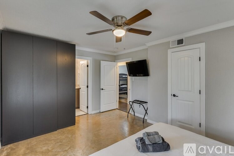 A room with a ceiling fan and a bed.