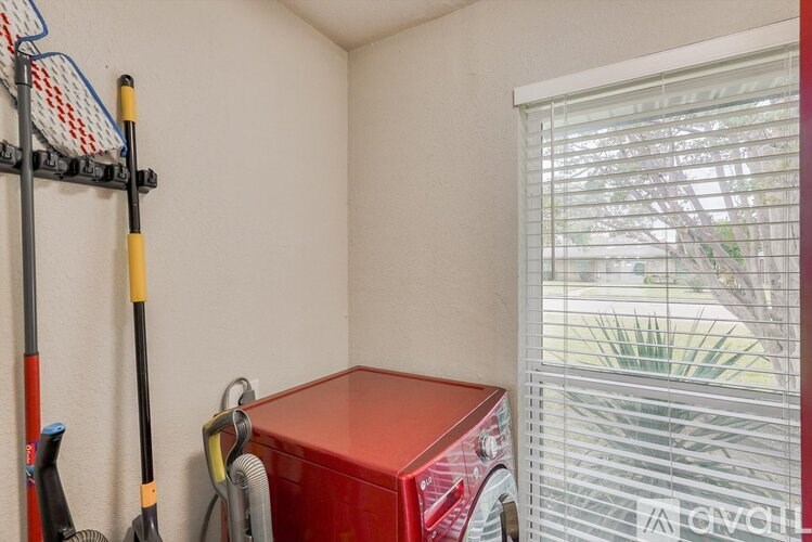 A red box sits on a shelf next to a window with blinds.
