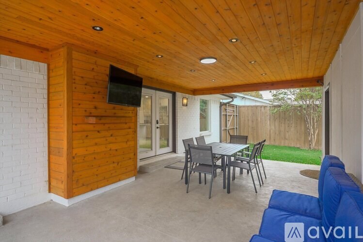 A wooden room with a TV on the wall and a table with chairs.