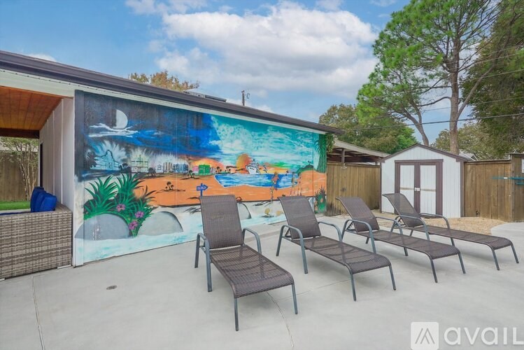 A pool area with a mural on the wall and lounge chairs.
