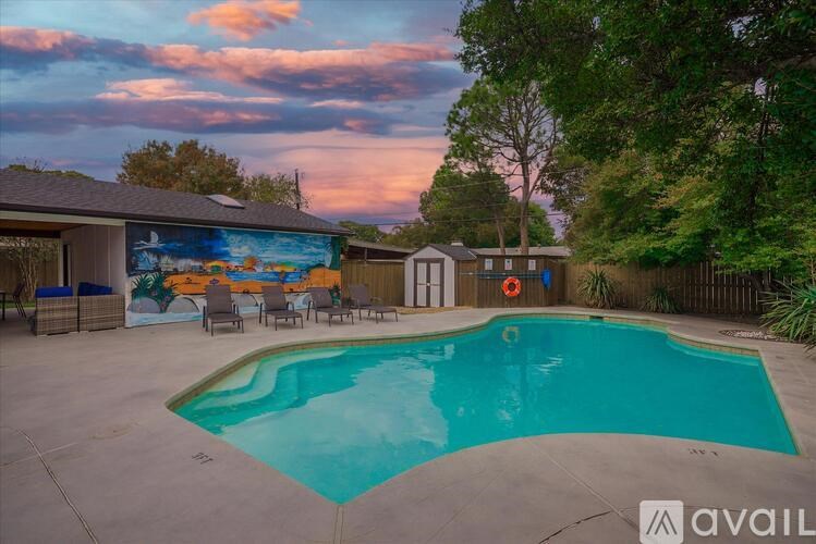 A pool with a mural on the wall and a sunset sky.