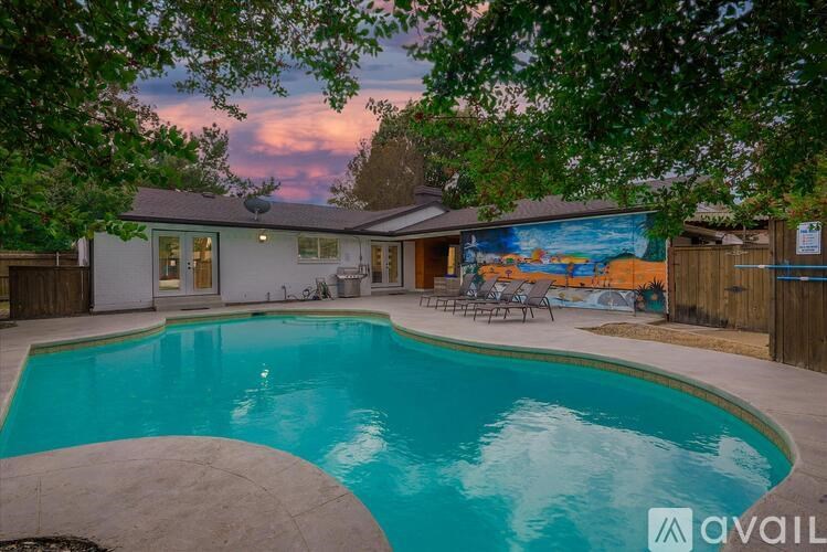 A pool in a backyard with a house and trees.