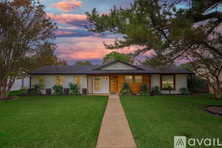 A house with a brown door is surrounded by a green lawn.