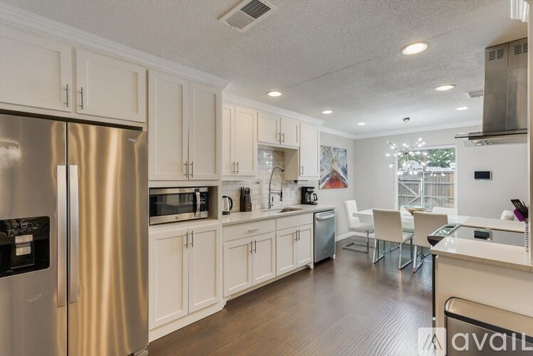 A kitchen with a refrigerator, microwave, oven, and sink.