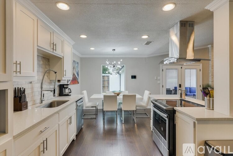 A modern kitchen with white cabinets and a wooden floor.