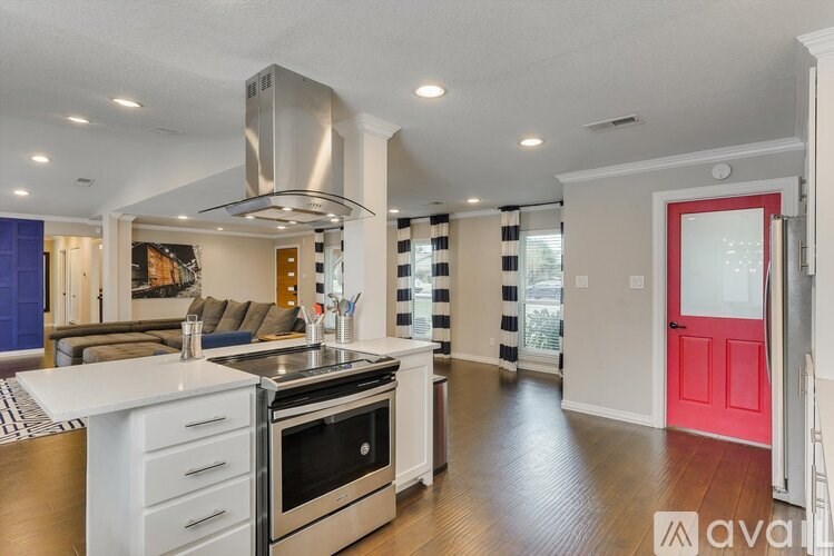A modern kitchen with a red door and a stainless steel range hood.