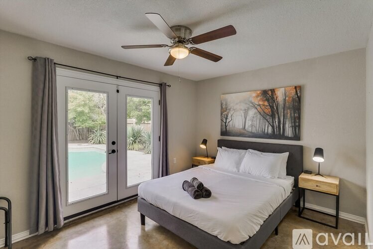 A bedroom with a bed, a ceiling fan, and a painting on the wall.